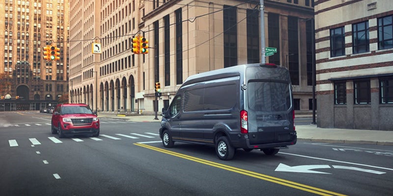 Rear view of a Ford Transit van, driving through a city.